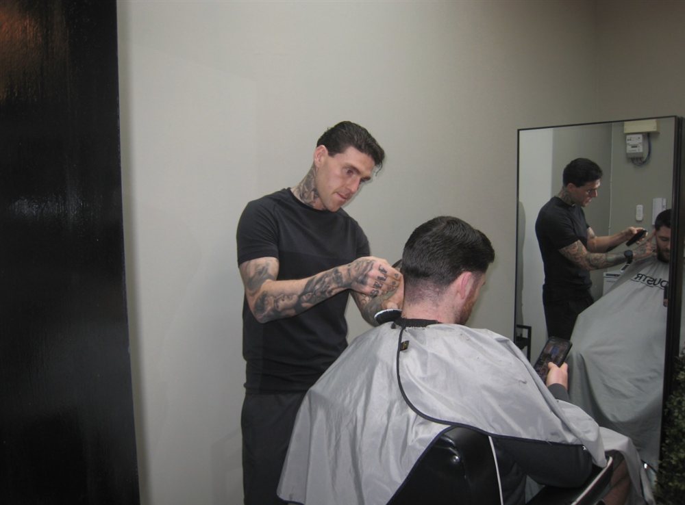 A barber finishing a client's neckline with clippers